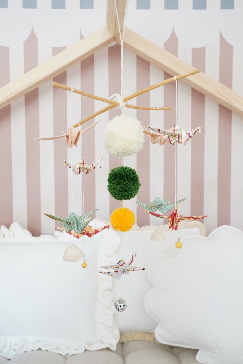 playful origami nursery mobile with colorful yarn pompoms and spinning paper cranes