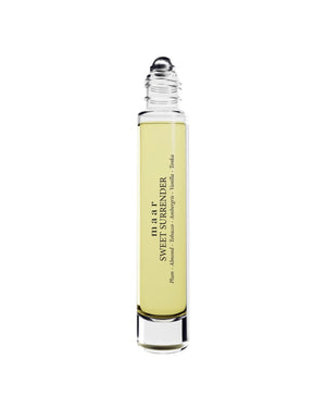 close-up of sweet surrender perfume oil bottle resting on soft fabric, a comforting unisex scent of plum and almond
