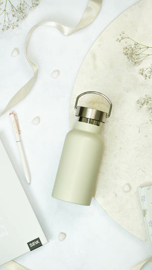 confident beige stainless steel water bottle on a bold adventure-ready background