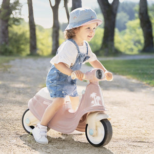 bold front view of a pink retro ride-on scooter for toddlers on a sunny adventure path