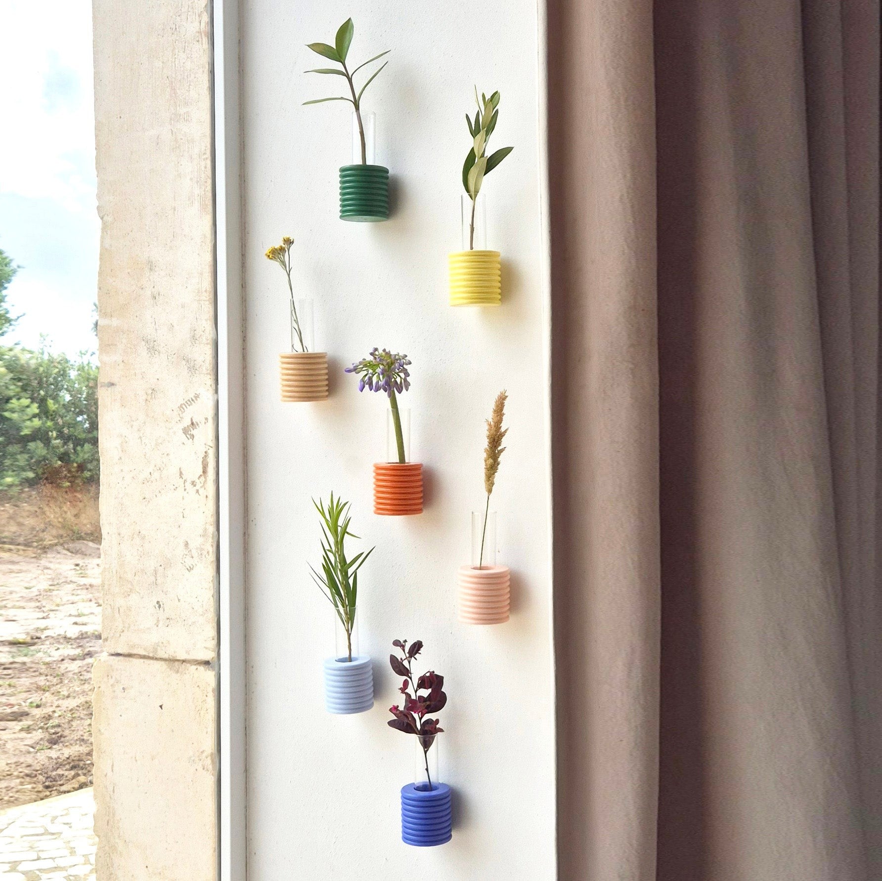 a soft green ribble wall vase with a single white daisy against a cozy, sunlit wall