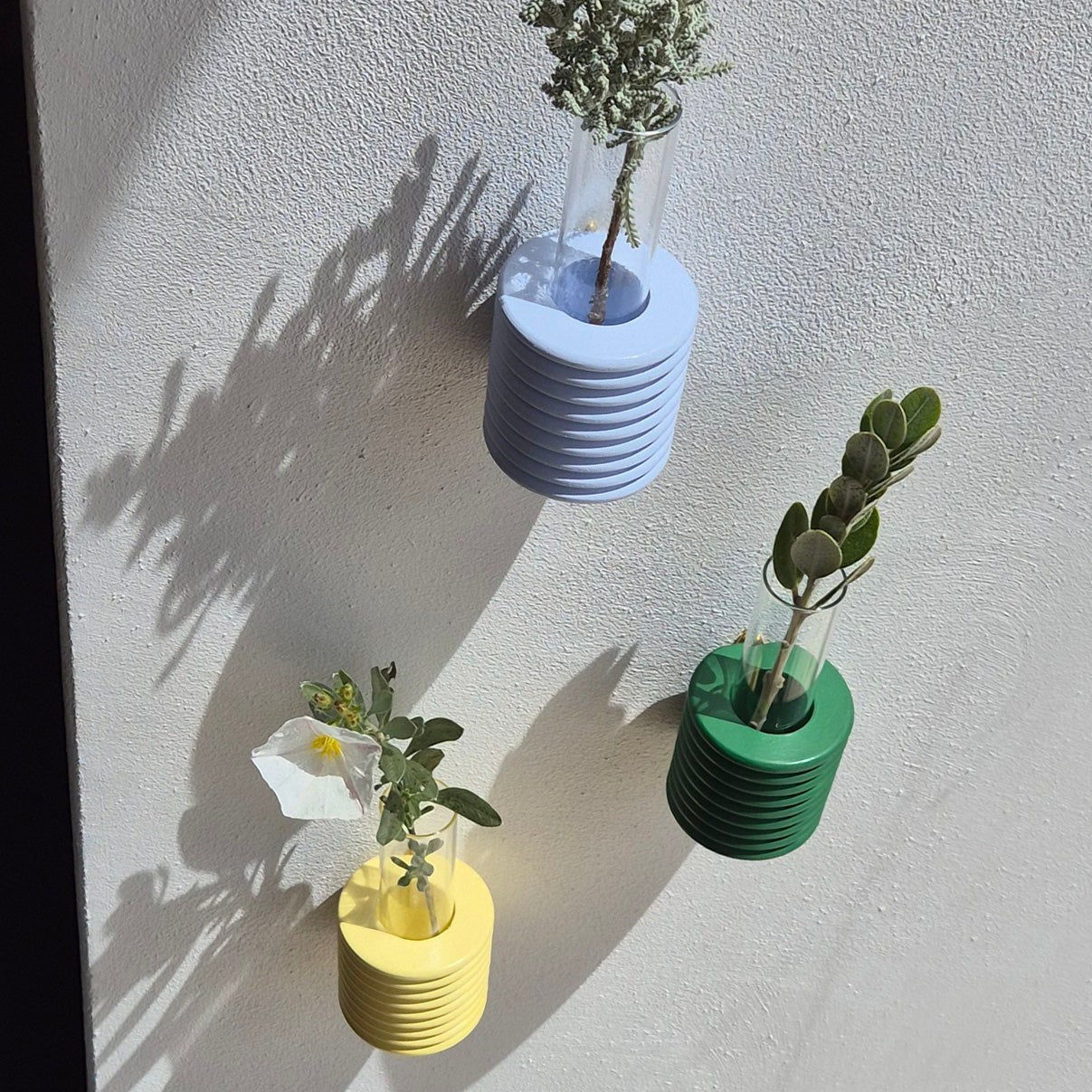 playful light blue ribble wall vase with a single cheerful wildflower on a sunny yellow background