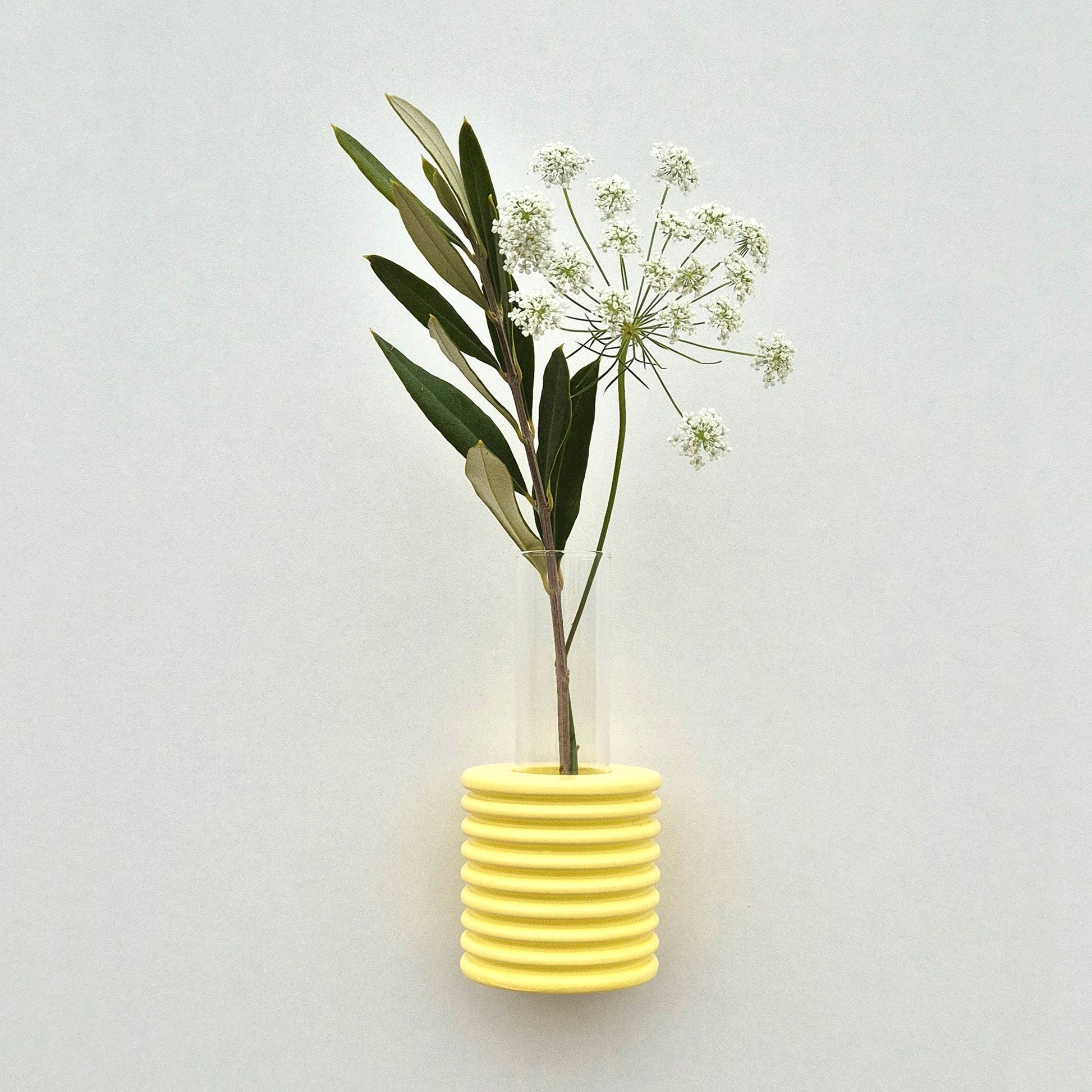 bold yellow ribble wall vase made of beech wood hanging solo on a clean white wall