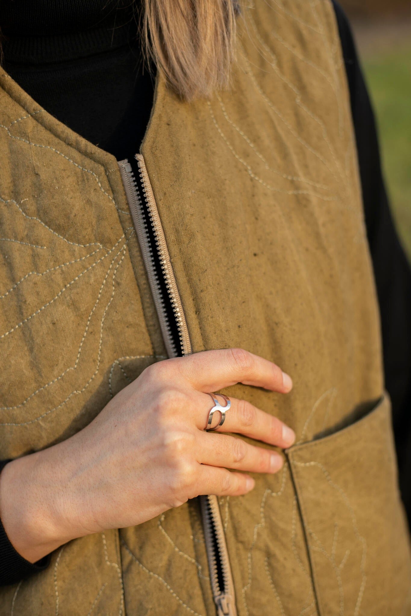 a bold close-up of the polished stainless steel ring x catching a sharp, dramatic light