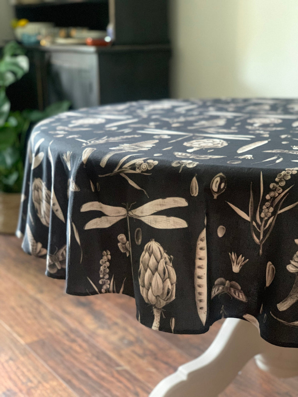 a playful close-up of the round cotton tablecloth's seeds carbon print on a sunlit garden table