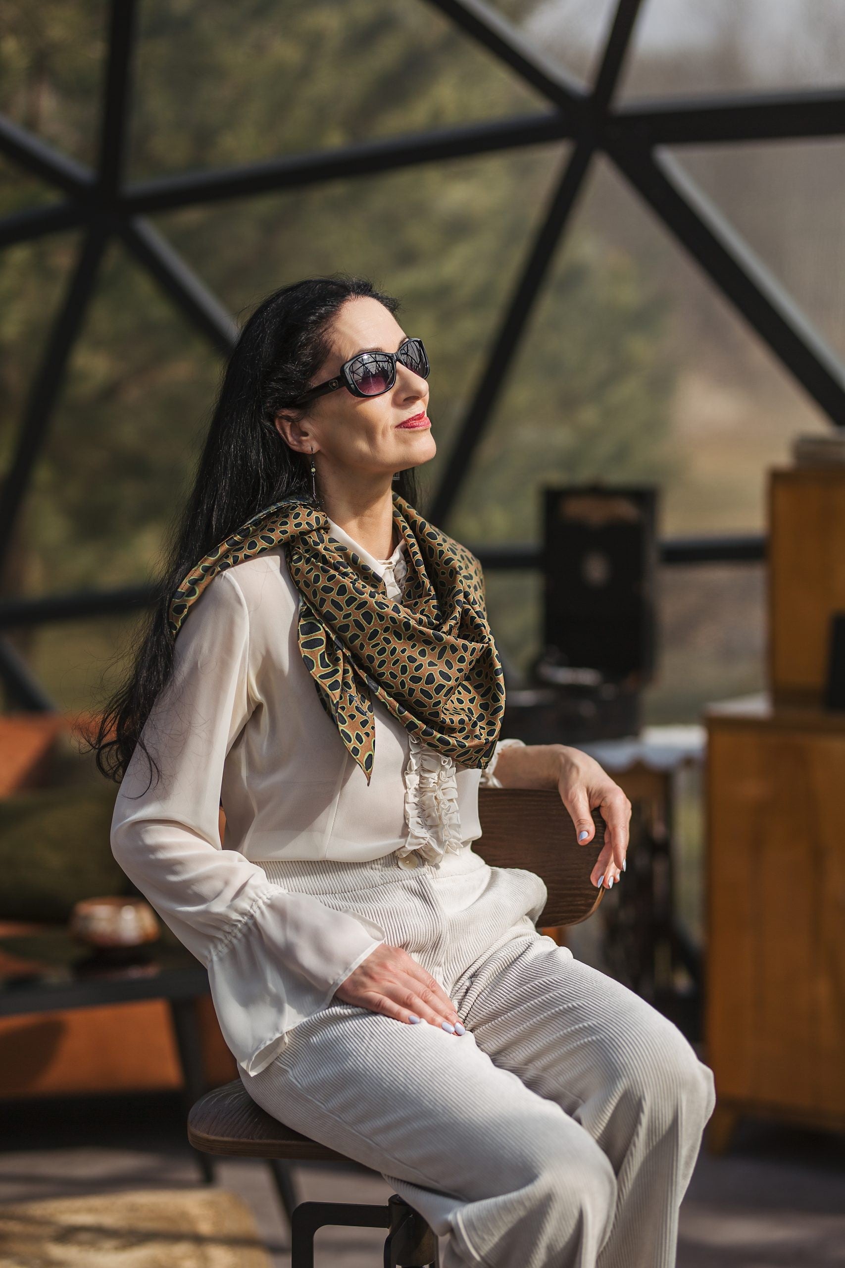 a bold leopard print silk scarf tied confidently around the neck with a dramatic sheen