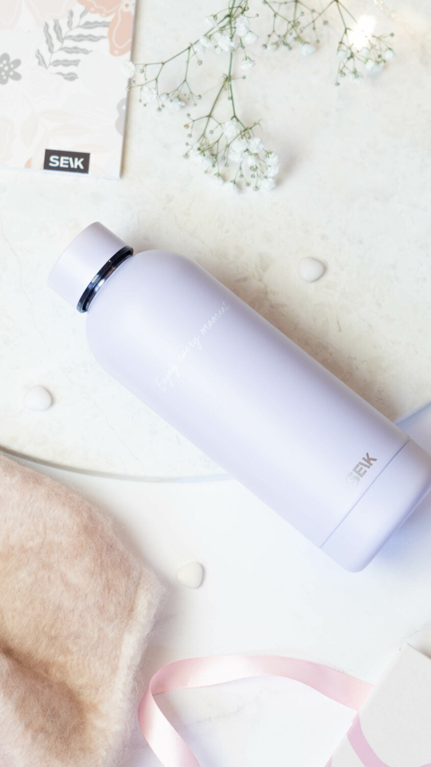a soft lilac water bottle held in hand, casting a gentle morning shadow