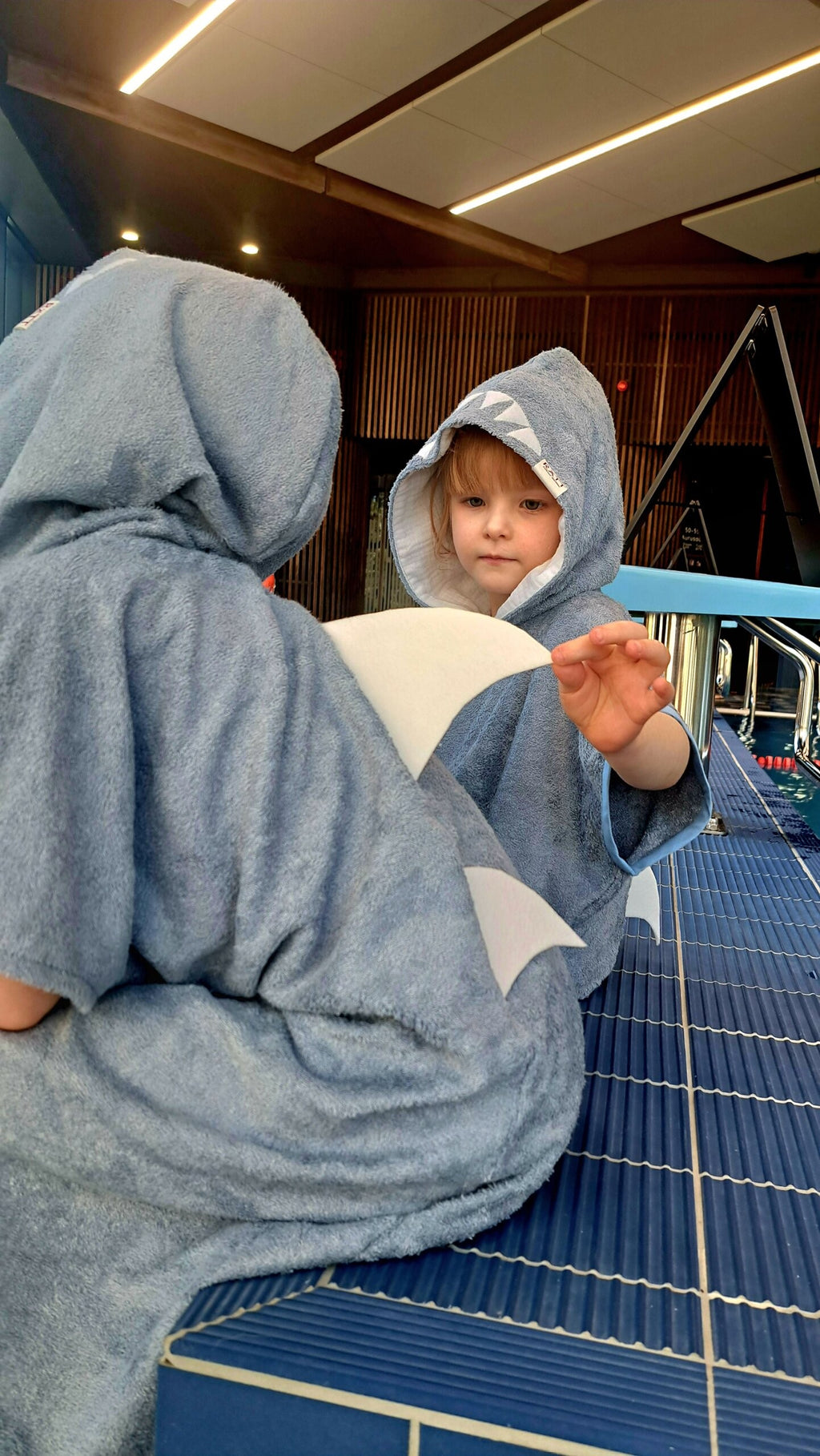 toddler laughing in a playful shark poncho with a hood and pockets after a beach day