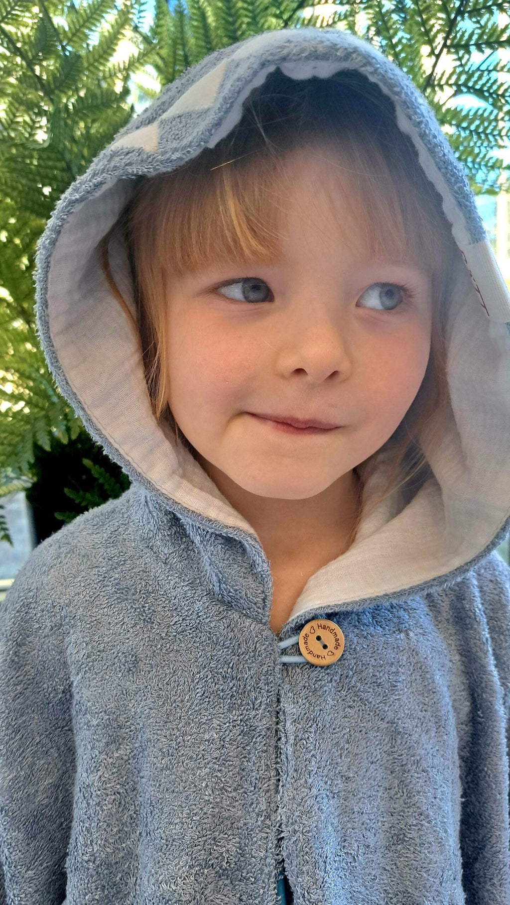 toddler in shark poncho showing the soft bamboo terry fabric and two handy pockets up close