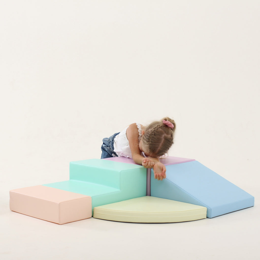 child climbing on a soft pastel foam corner climber in a sunlit playroom