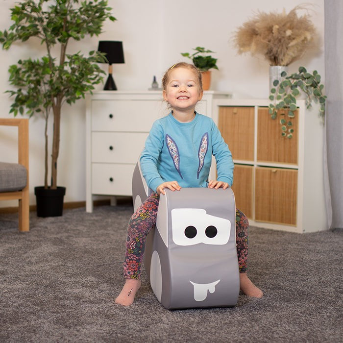 smiling toddler riding grey soft play car, giggling while rocking on eco-friendly foam toy