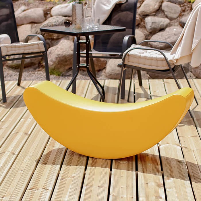 happy toddler rocking on a bright yellow banana toy, giggling with joy in a sunlit playroom