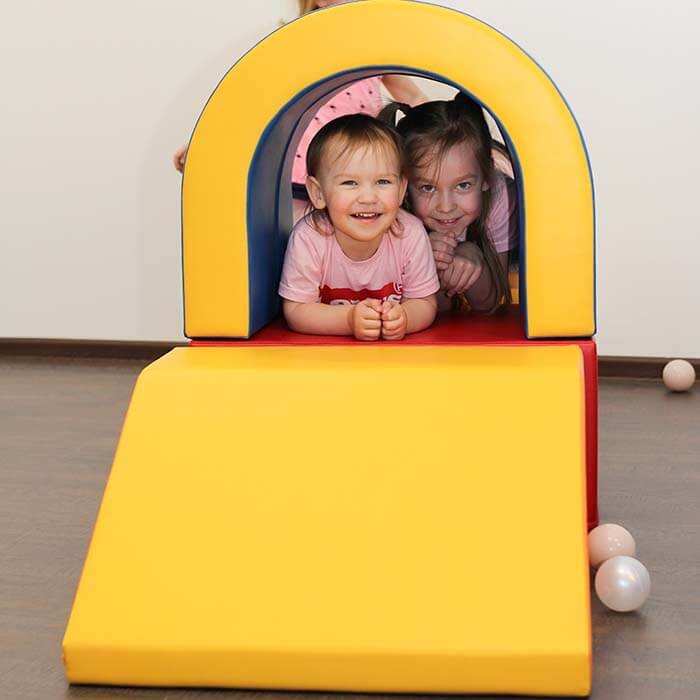 multicolor soft play tunnel with kids laughing, crawling through vibrant eco-leather foam for endless fun