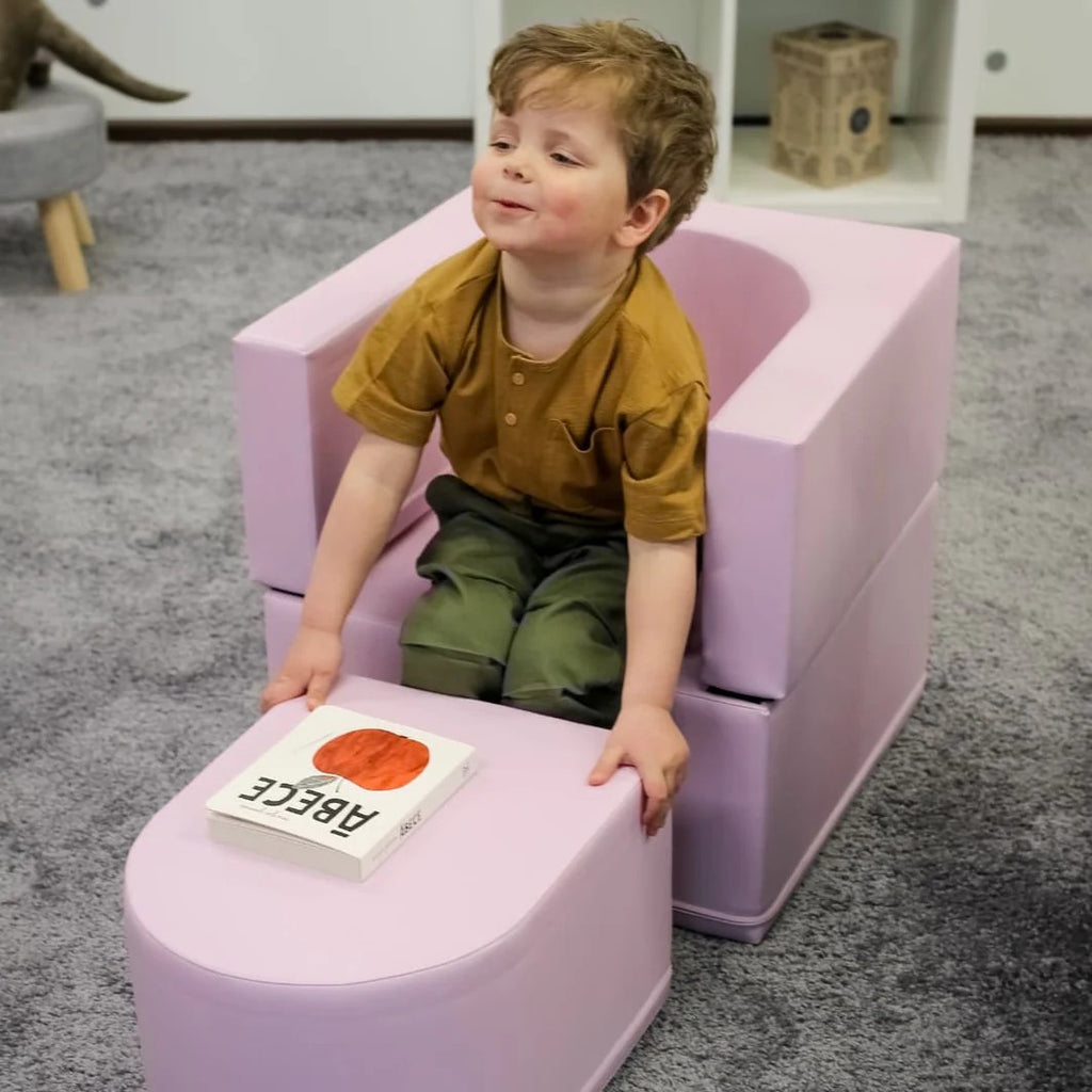 a sophisticated pink snoozy sofa chair for kids, elegantly lit in a modern playroom setting