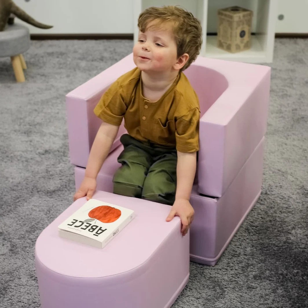 a sophisticated pink snoozy sofa chair for kids, elegantly lit in a modern playroom setting