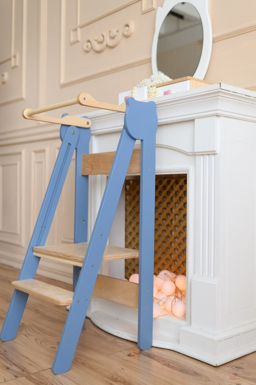 foldable baltic birch step stool for kids folded flat against a sunny kitchen wall