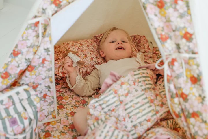 kids peeking out from the floral curtain window of their cozy green garden teepee tent