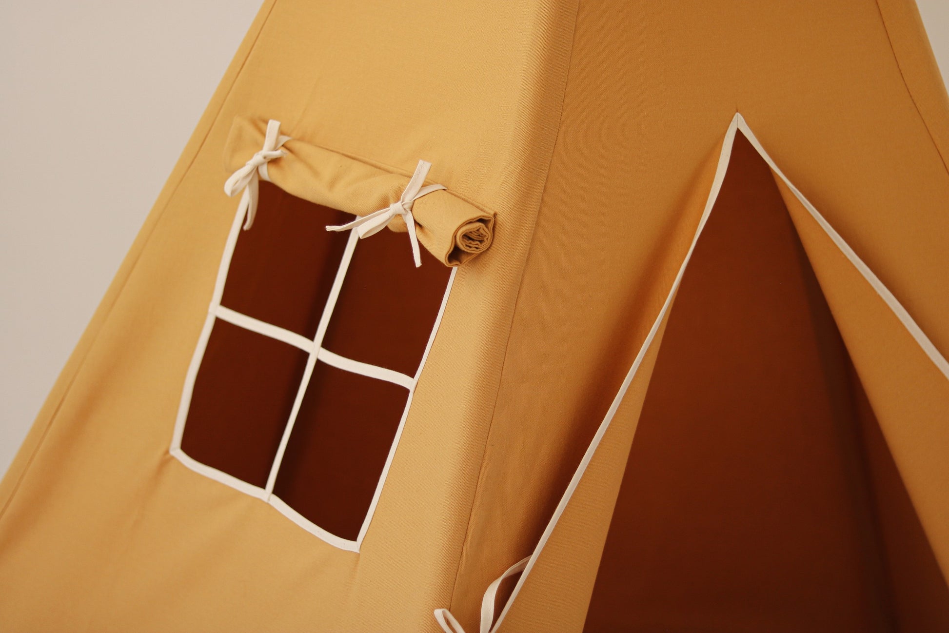 bold orange handmade kids teepee tent with pine poles in a bright playroom setting