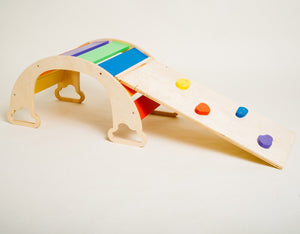bold rainbow ramp with climbing rocks on a vibrant playroom floor