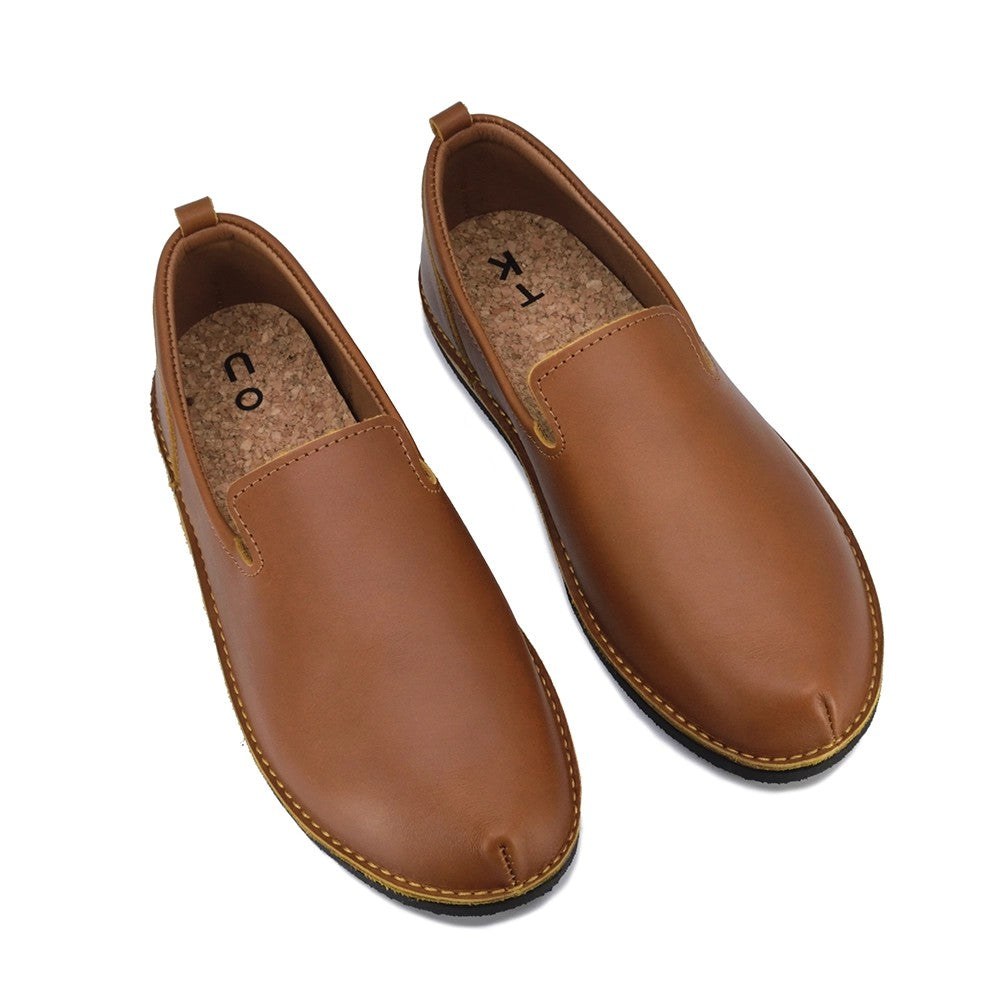 soft ocre leather london loafers with cushioned cork insole, side view on warm wooden background