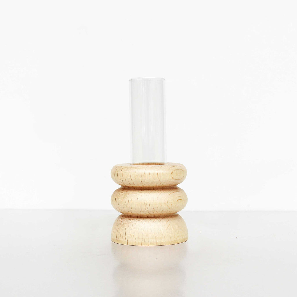 playful short totem wooden vase with a single bright flower on a sunlit windowsill