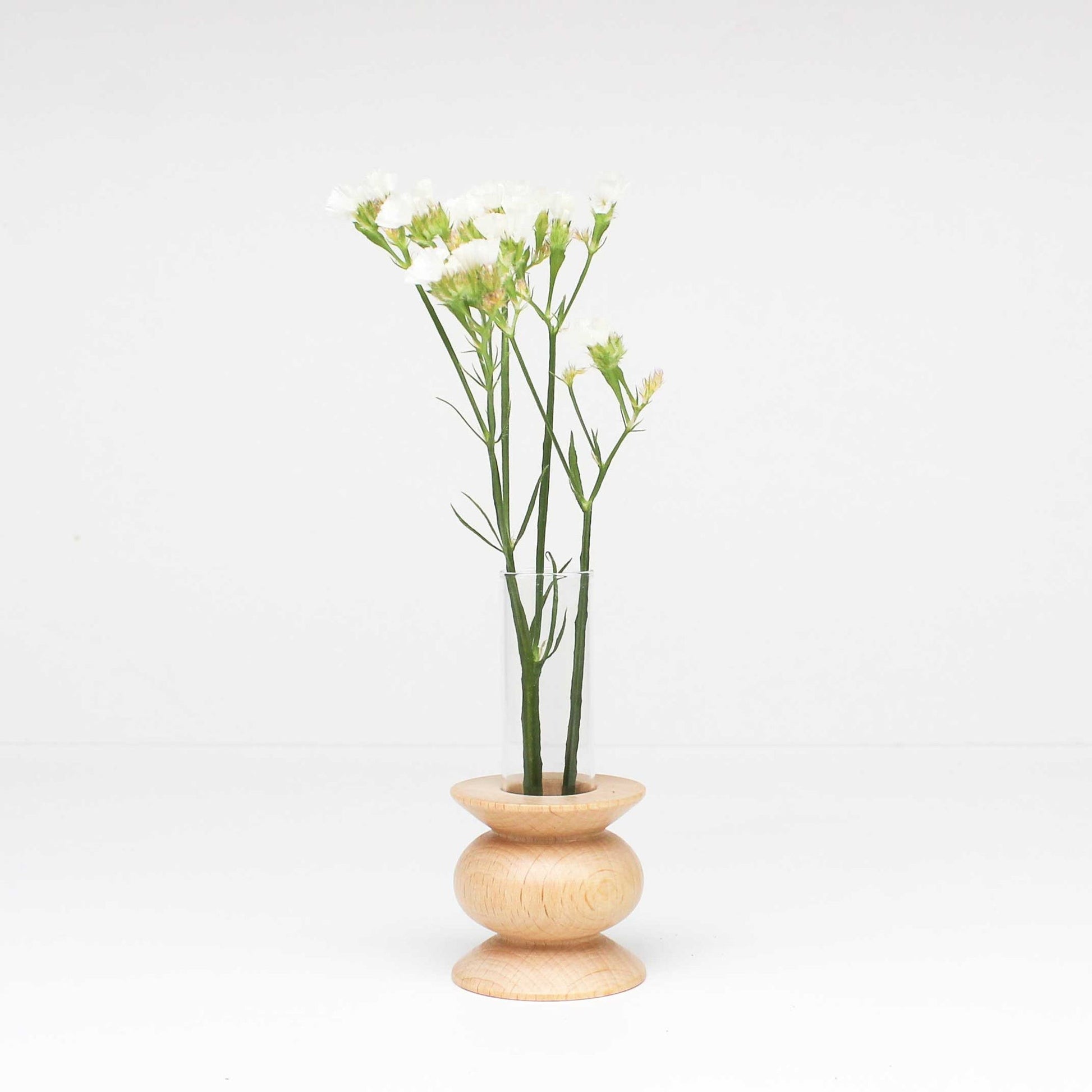 confident close-up of a solid beech totem vase with a sleek glass tube on a modern table