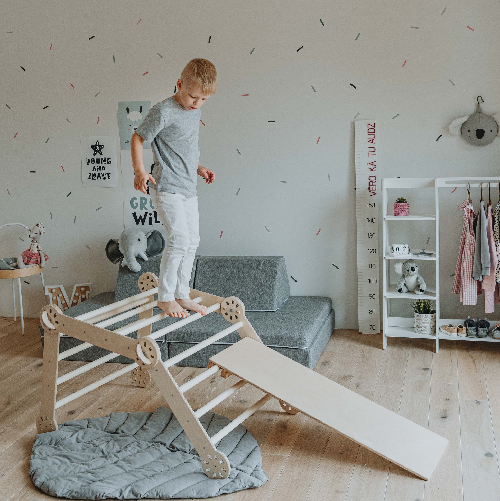 a playful toddler climbing the foldable montessori triangle with a sunny backdrop, giggling with joy