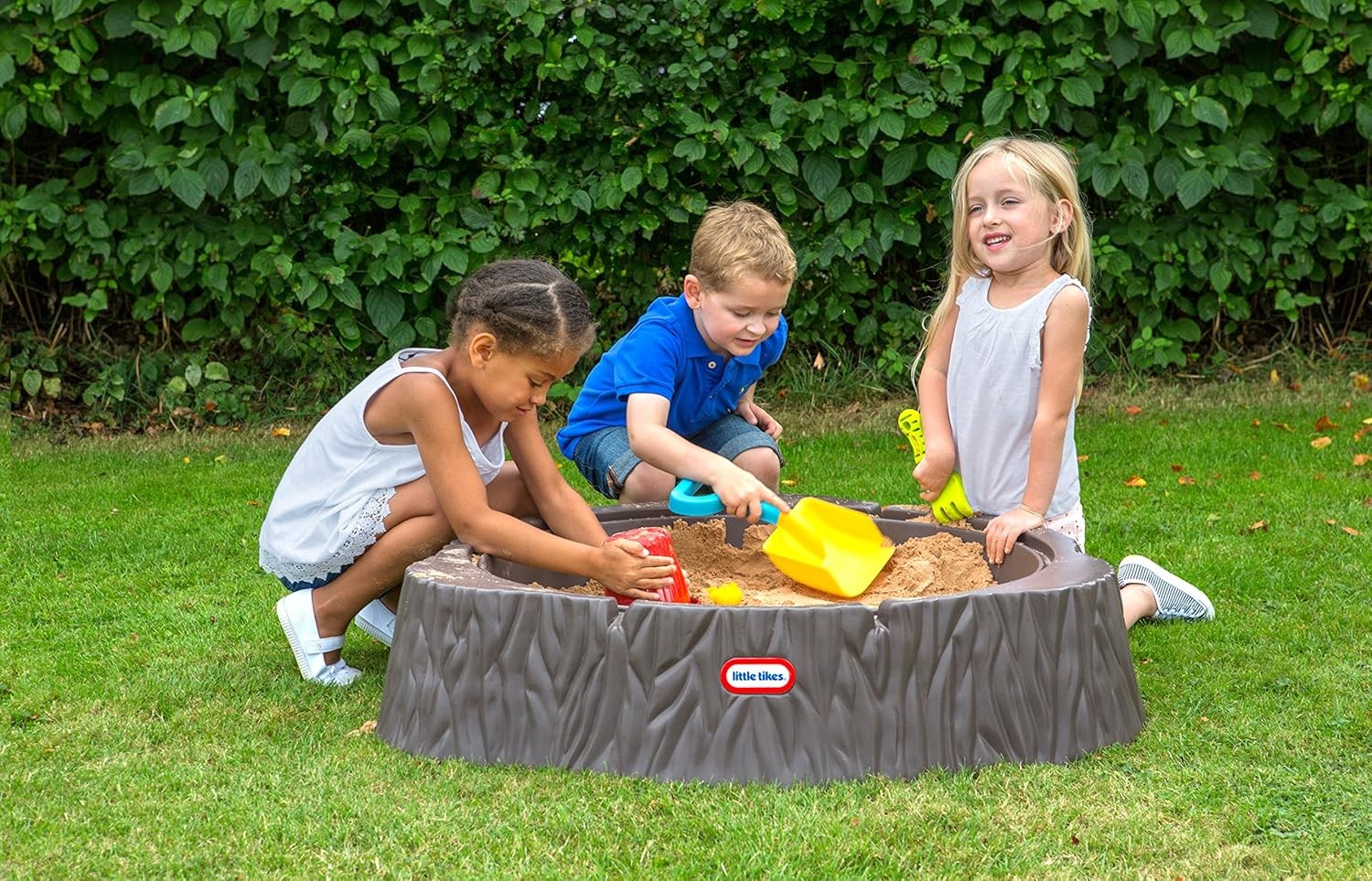 a soft-lit view of the enchanted tree trunk sandbox with its cozy cover on, nestled in a peaceful garden