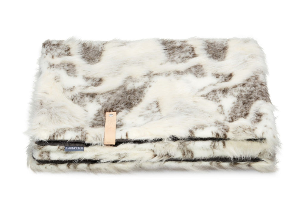 soft brown and white tosse blanket draped invitingly over a cozy chair