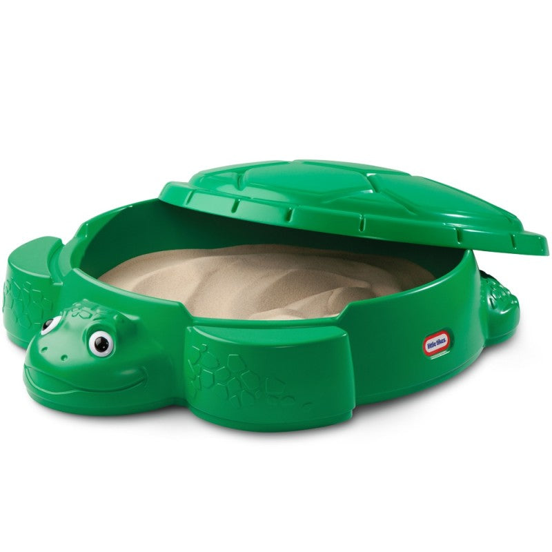 kids laughing in a bright green turtle sandbox with shell lid, sand toys scattered around