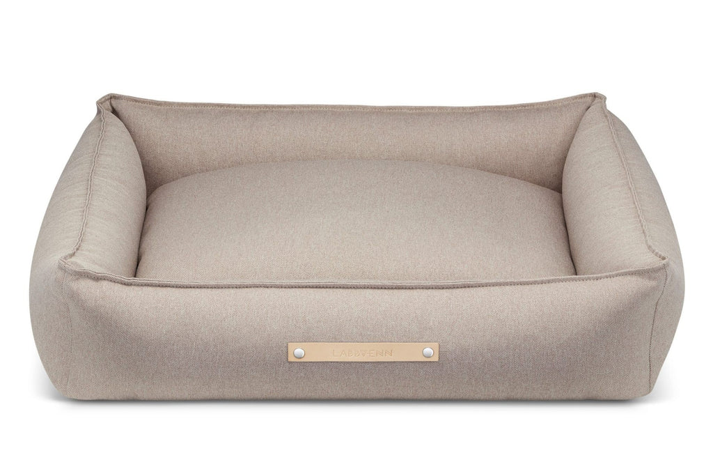 soft nut-brown töve dog bed in a cozy corner, offering a snug and secure retreat for a resting dog