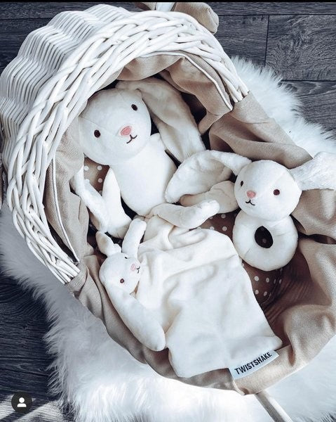 whitewashed wicker doll pram with beige bedding set shown in a practical nursery setting
