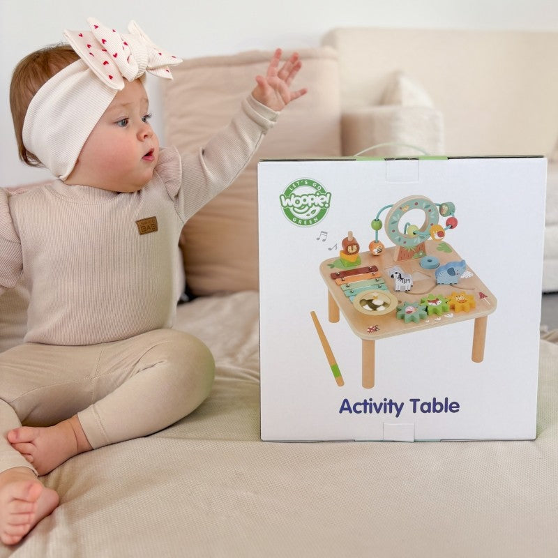 a toddler's hands playing with the colorful gear spinner on the woopie green 5-in-1 wooden activity table