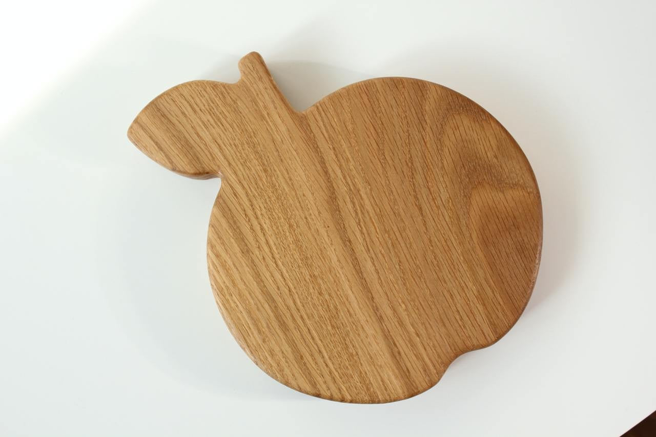 hand-polished wooden kids plate with apple design, natural oak finish, resting on a rustic kitchen table