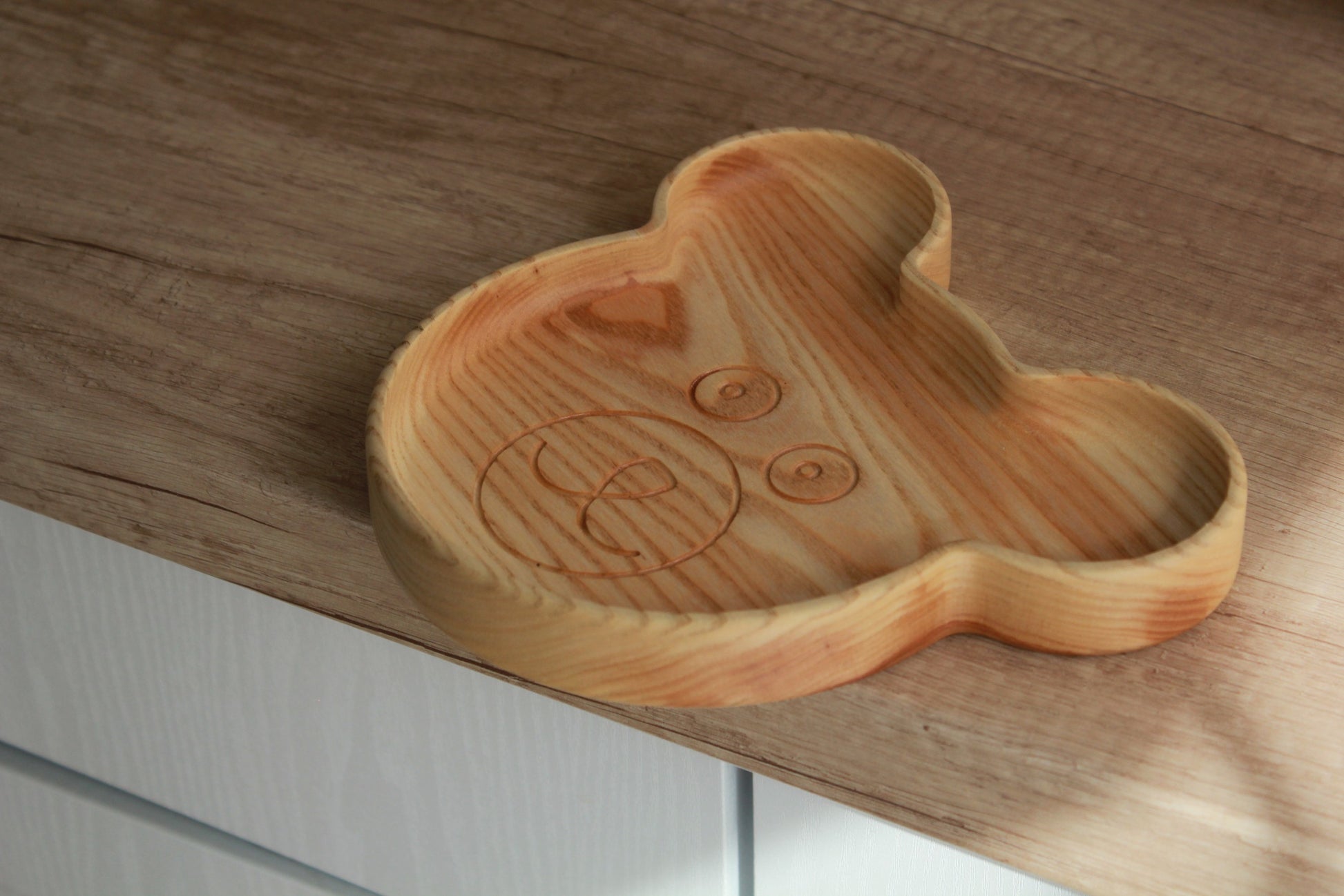 a soft, comforting close-up of a handcrafted wooden bear plate for kids on a cozy table