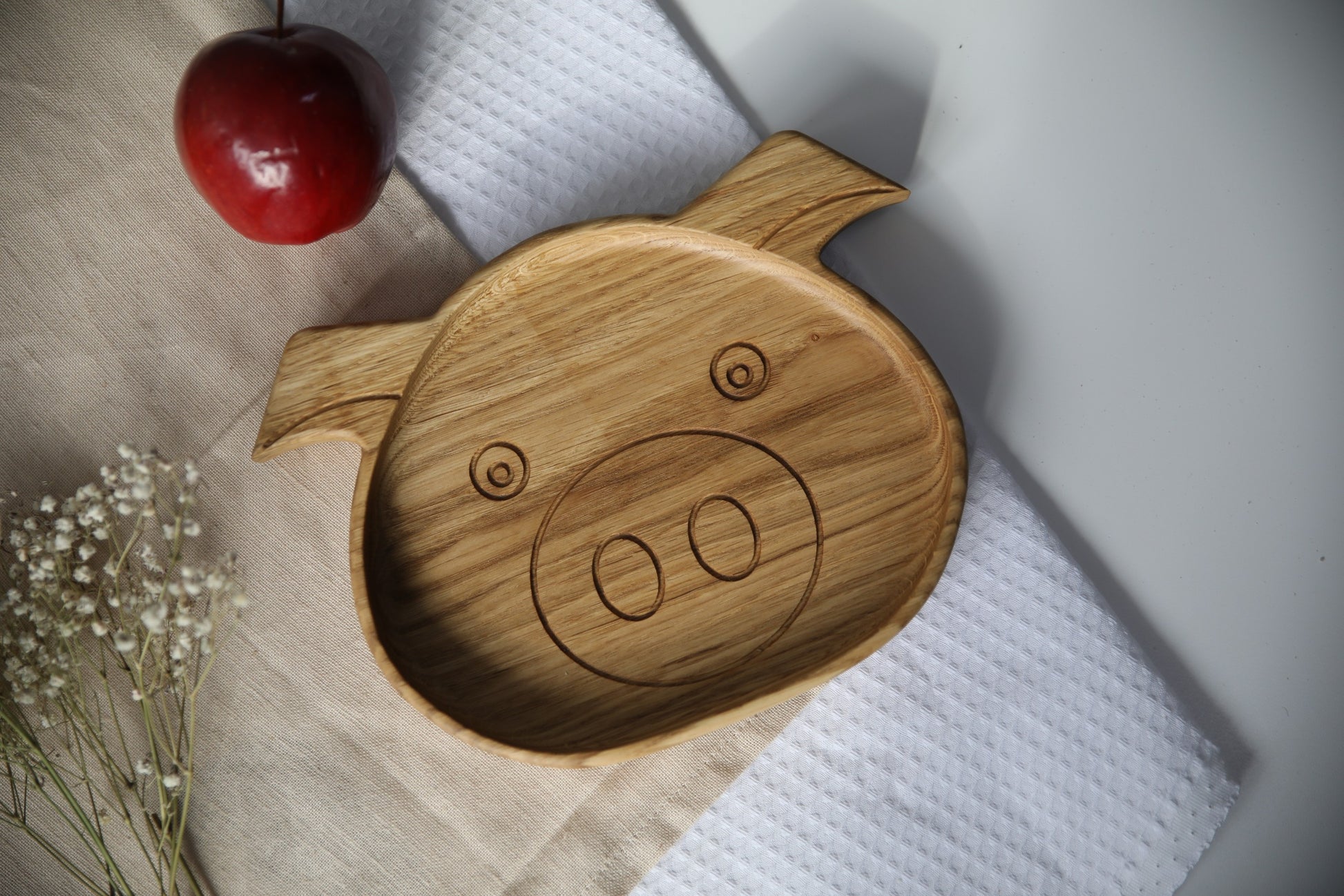 elegant hand-polished wooden kids plate with boar design, natural oak finish, resting on a rustic table