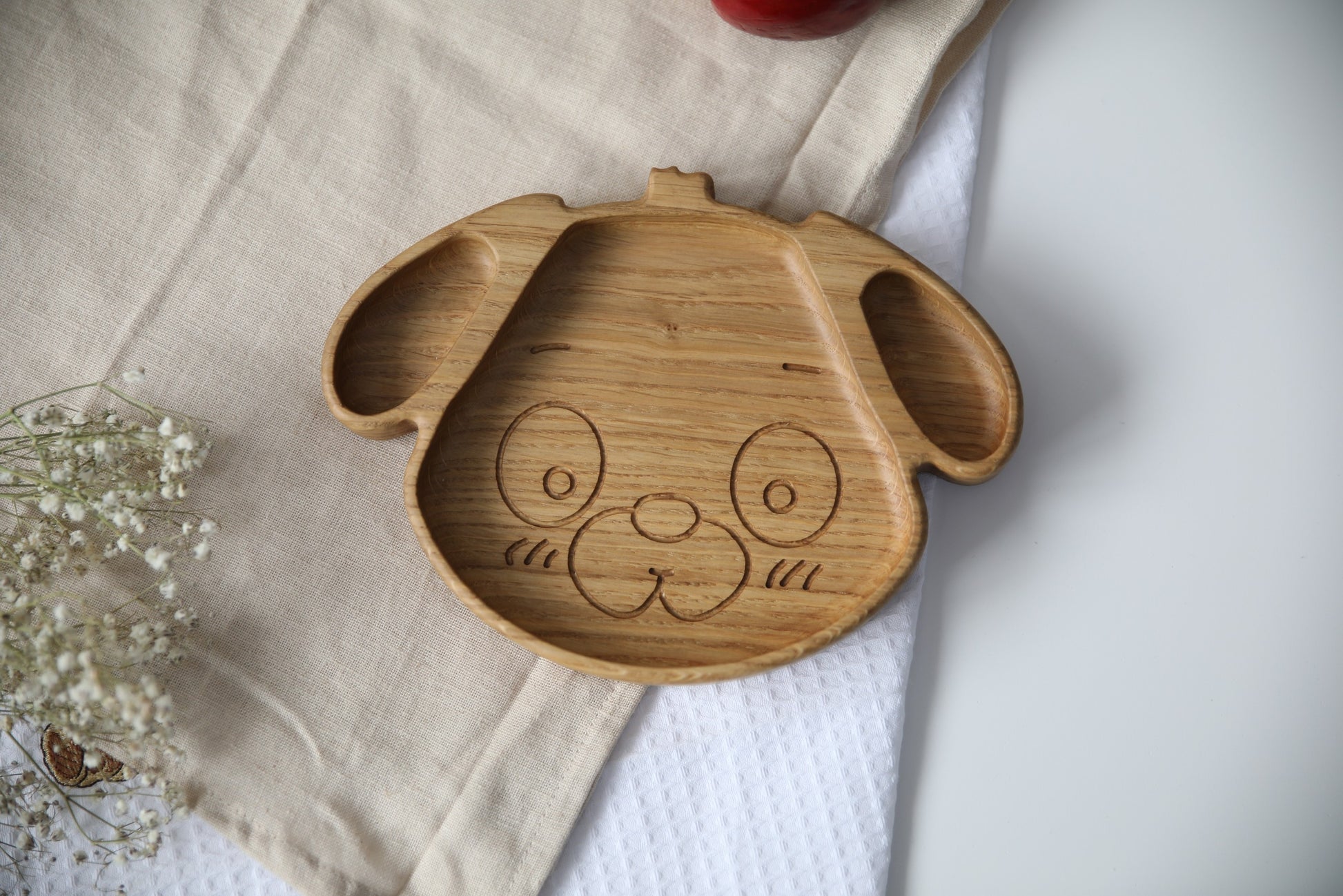 playful dog-shaped wooden plate for kids on a sunny table, handmade from natural oak with smooth polished surface