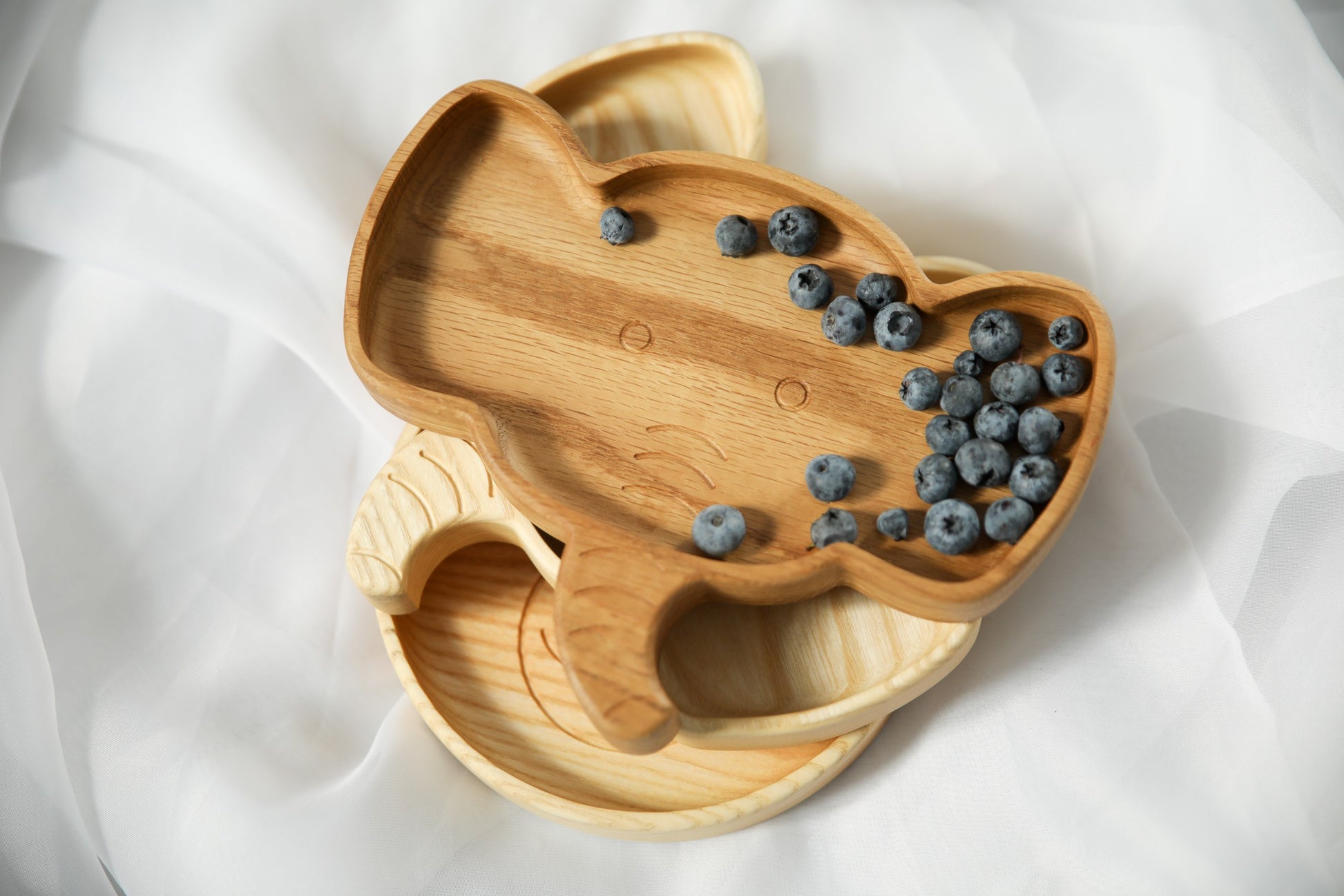 handmade wooden elephant plate for kids on a kitchen counter, showcasing its smooth oak surface and practical size