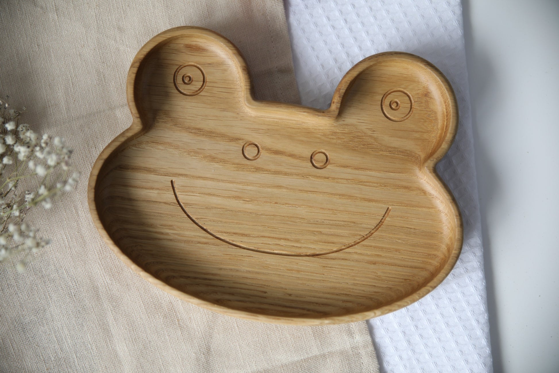 handmade frog-shaped wooden plate for kids on a rustic table, showcasing its smooth polished surface and natural wood grain