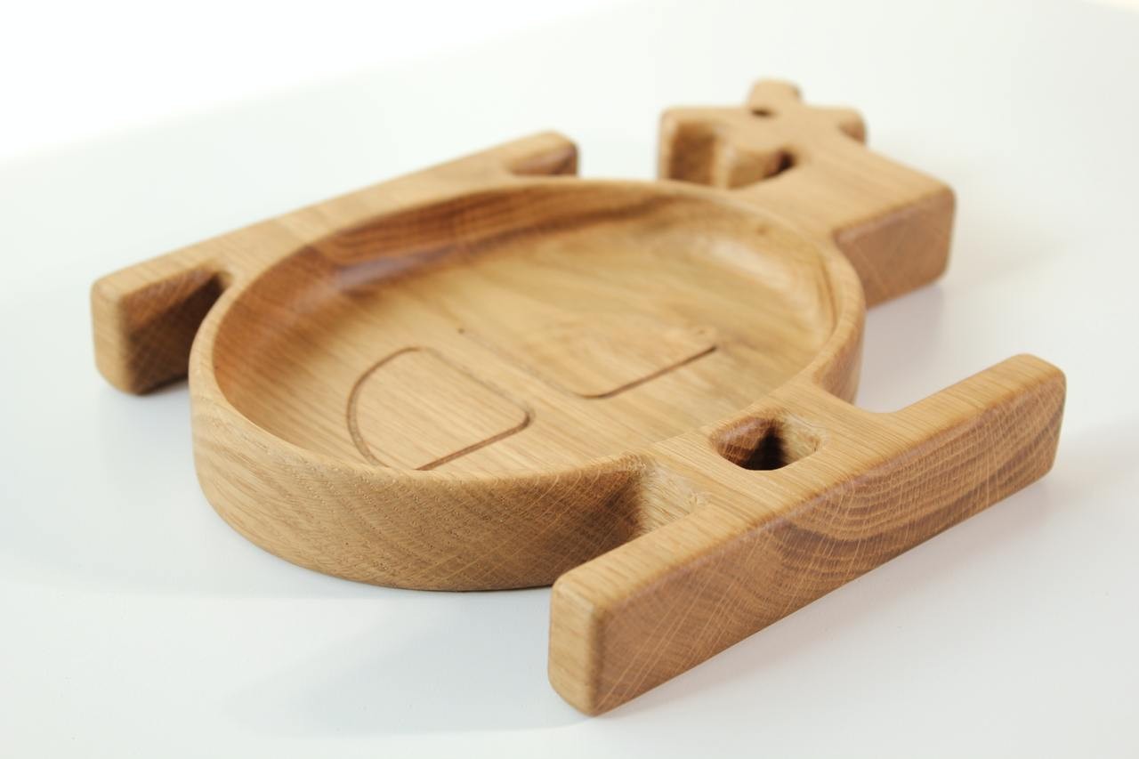 softly lit handmade wooden helicopter plate for kids, natural oak with smooth polished surface, resting on a cozy linen cloth