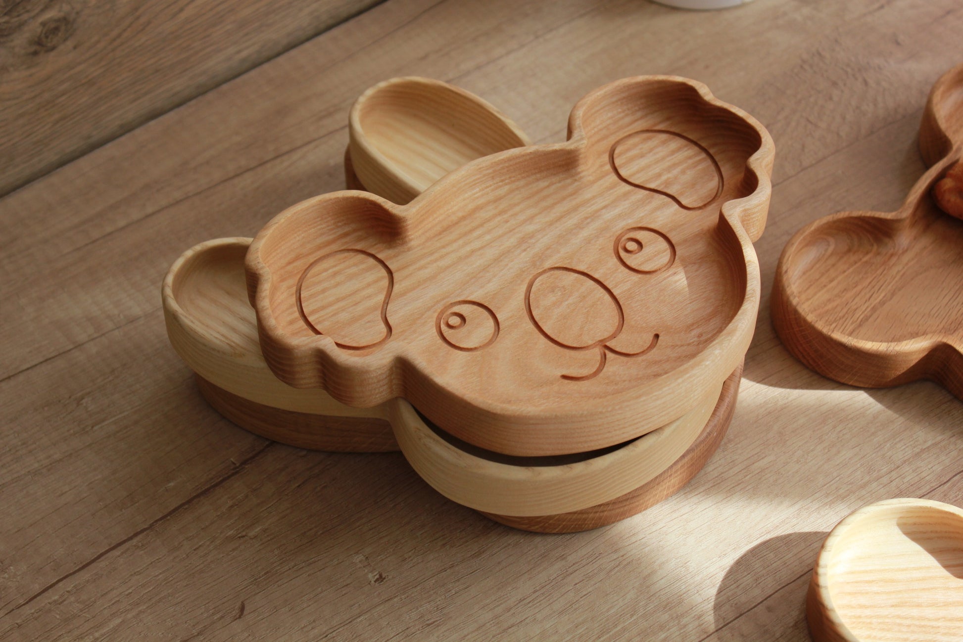 soft-lit wooden koala plate for kids, hand-polished oak with smooth curves, resting on a cozy kitchen table