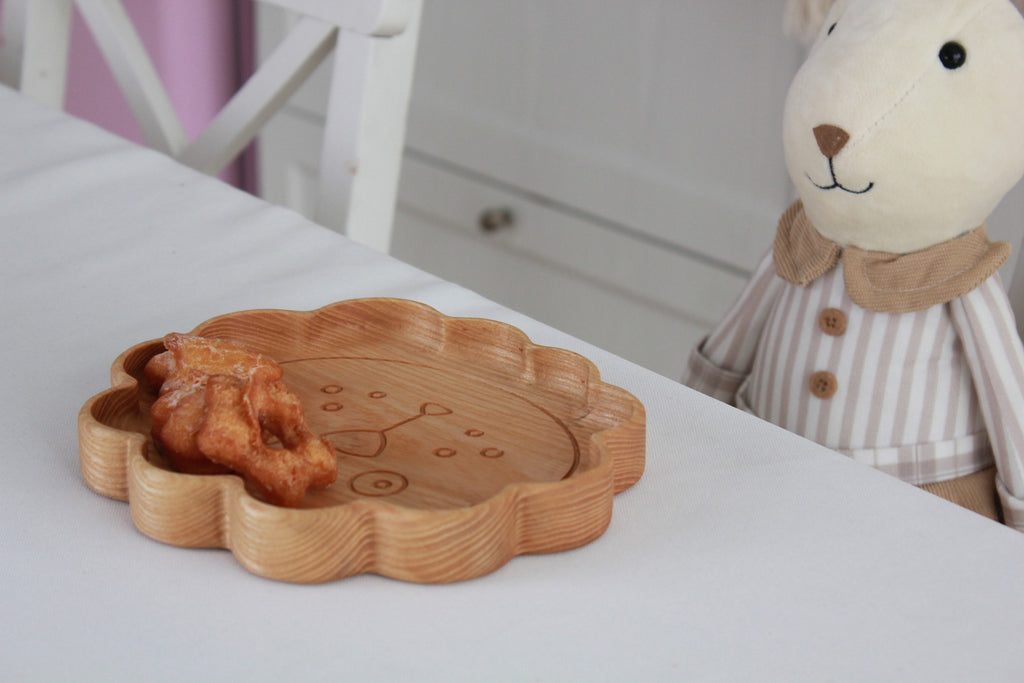 handmade wooden lion plate for kids on a kitchen counter, showcasing its smooth oak surface and functional design