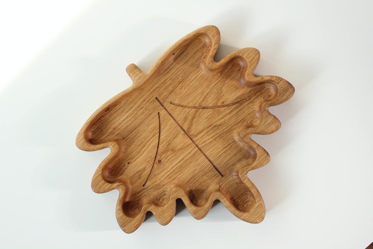 playful maple leaf wooden plate for kids on a sunlit table, showcasing its smooth hand-polished surface and natural grain