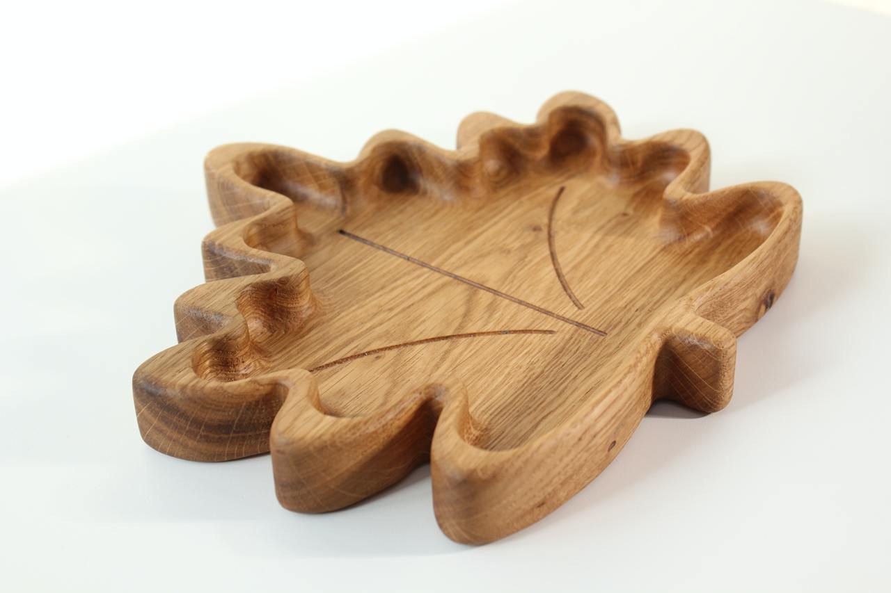 hand-polished wooden kids plate with maple leaf design, natural oak grain glowing in warm light