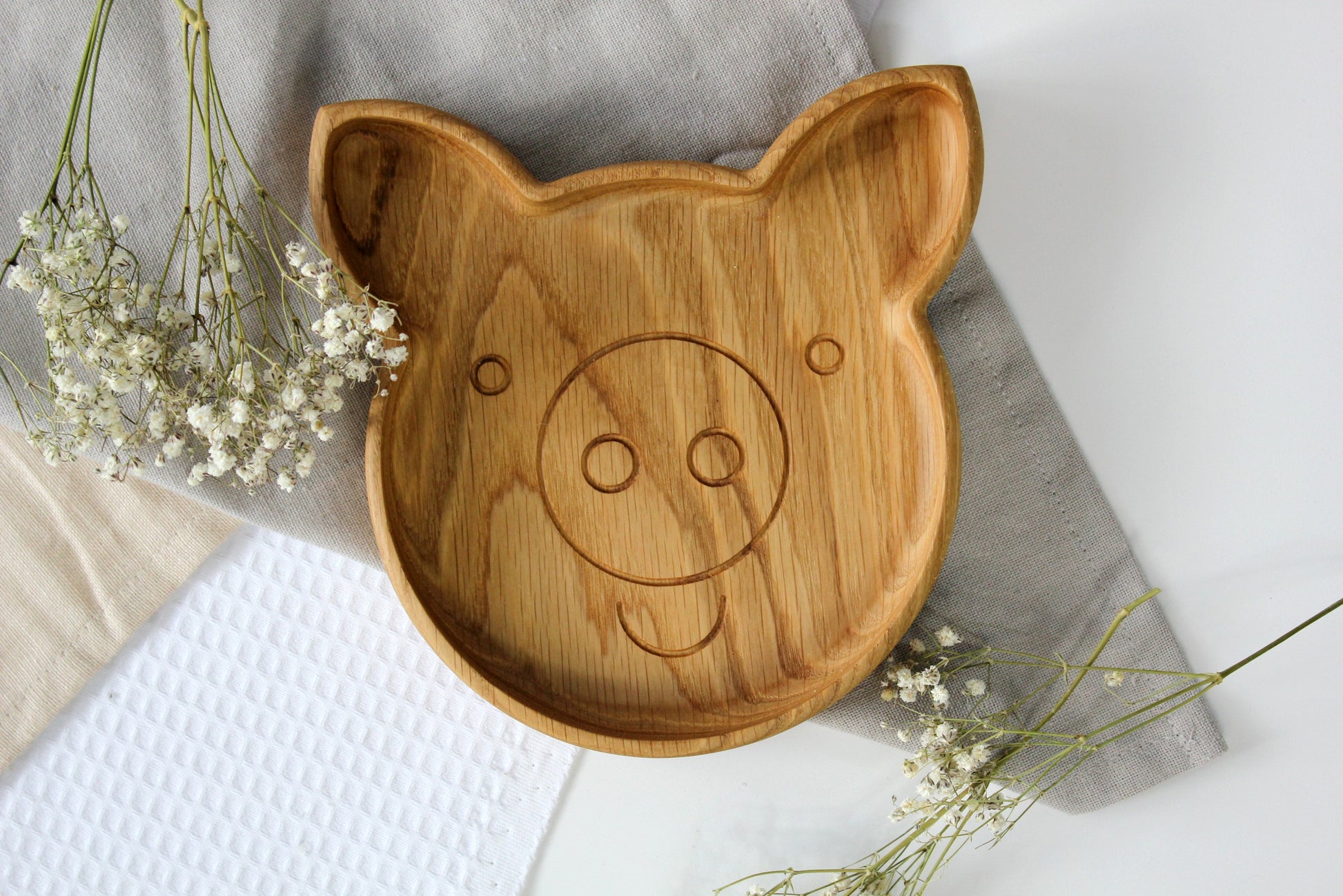close-up of a playful pig-shaped wooden plate for kids on a rustic table