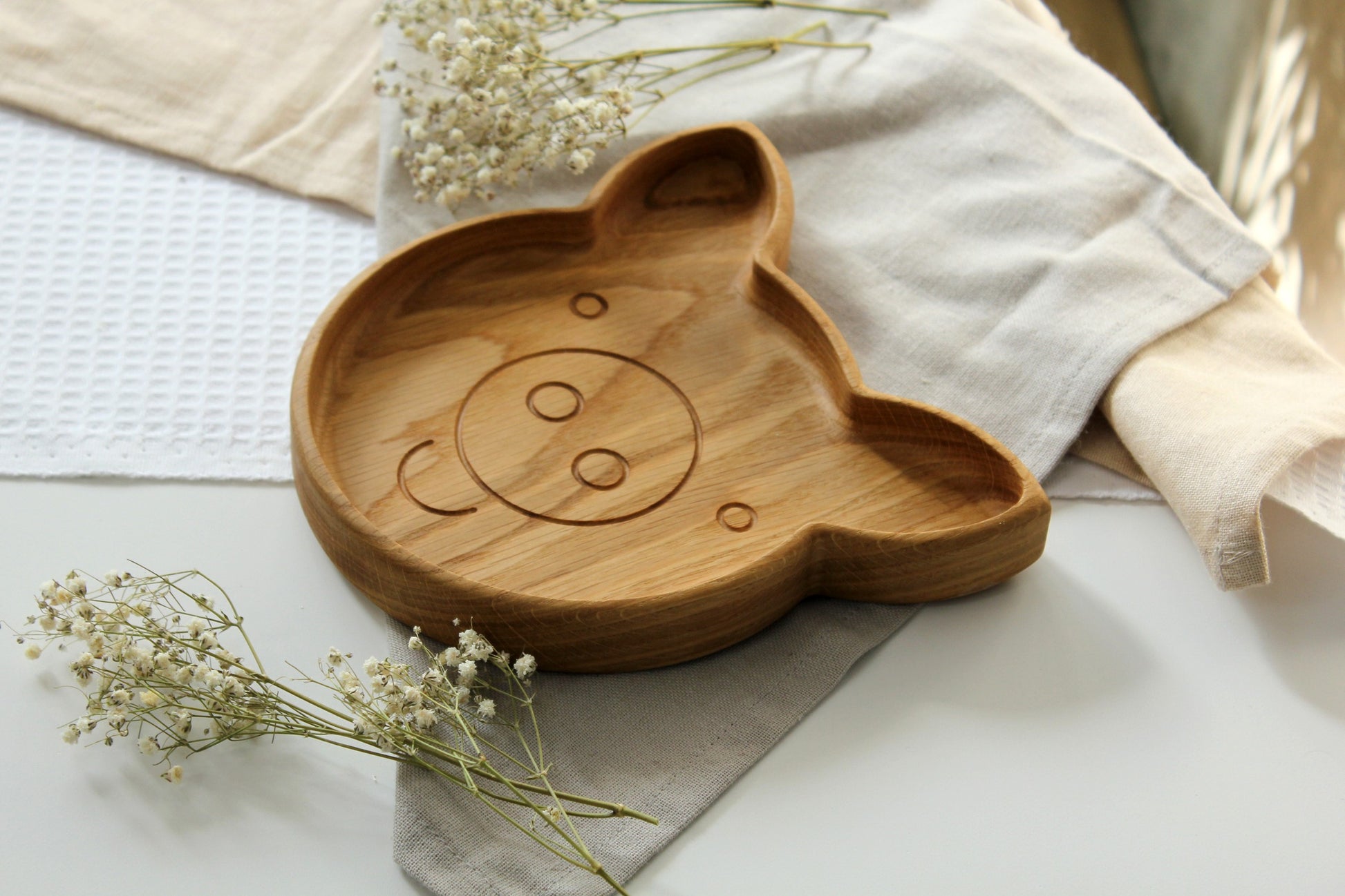 handmade wooden pig plate for kids on a kitchen table with care instructions nearby