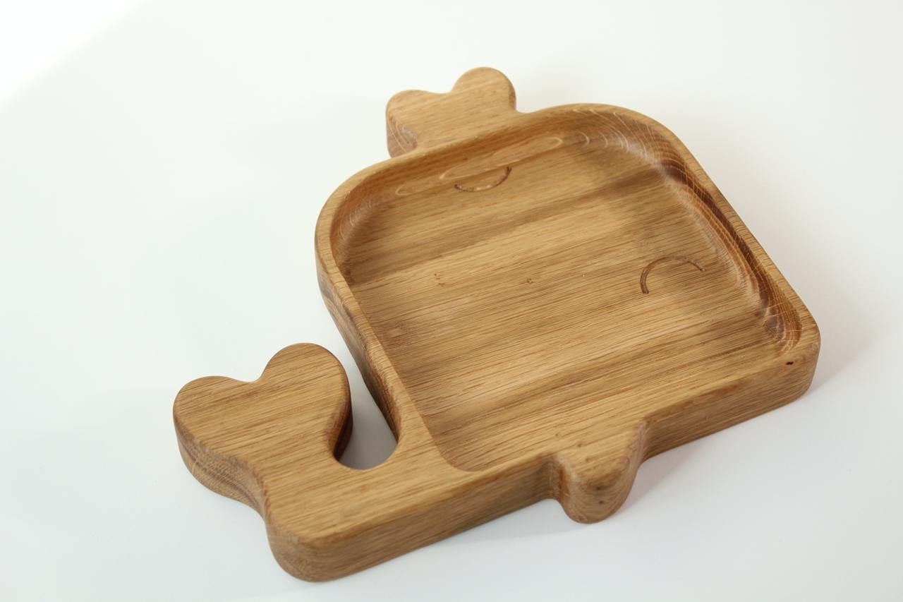 playful whale-shaped wooden plate for kids on a sunny table, handmade from smooth oak with optional engraving