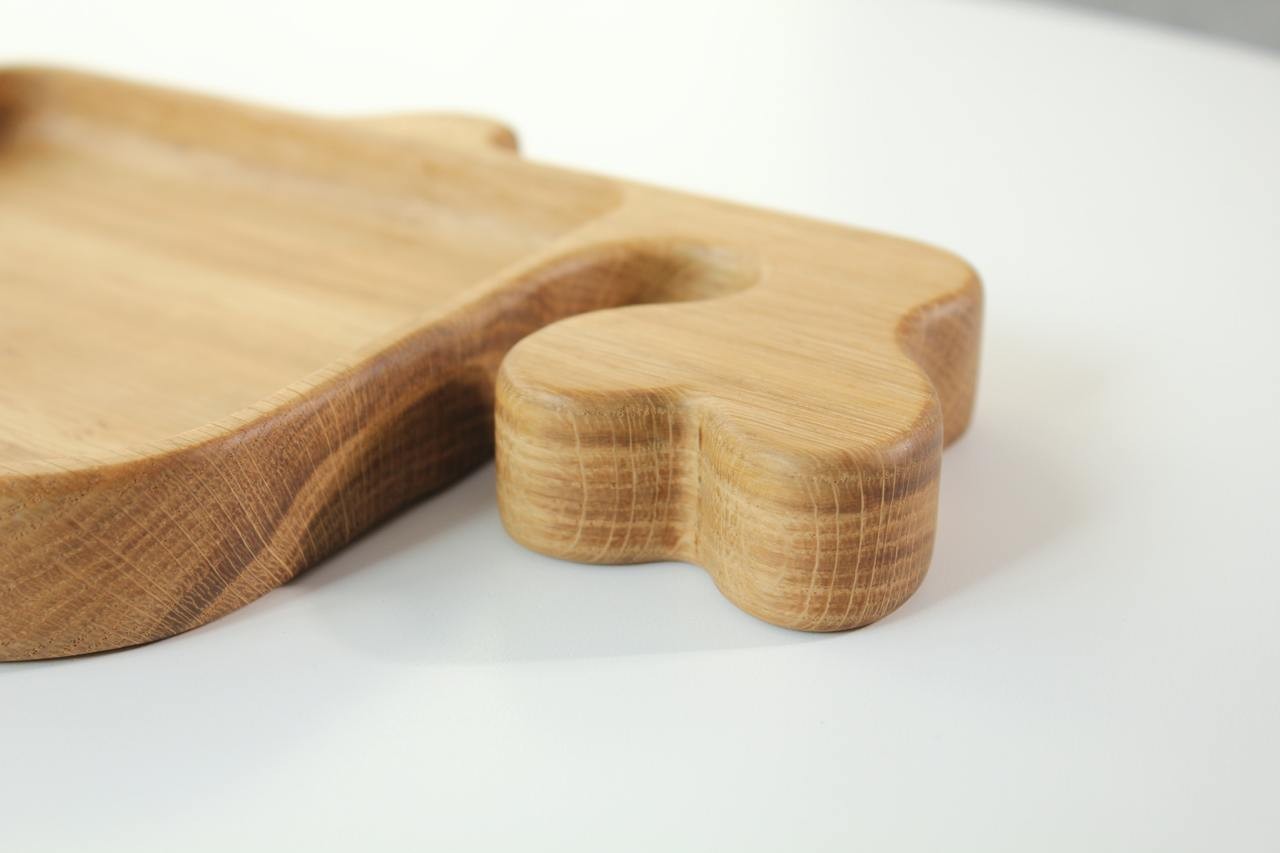 close-up of a handcrafted oak whale plate on a kitchen counter, showcasing its smooth food-safe finish and practical size for a child's meal