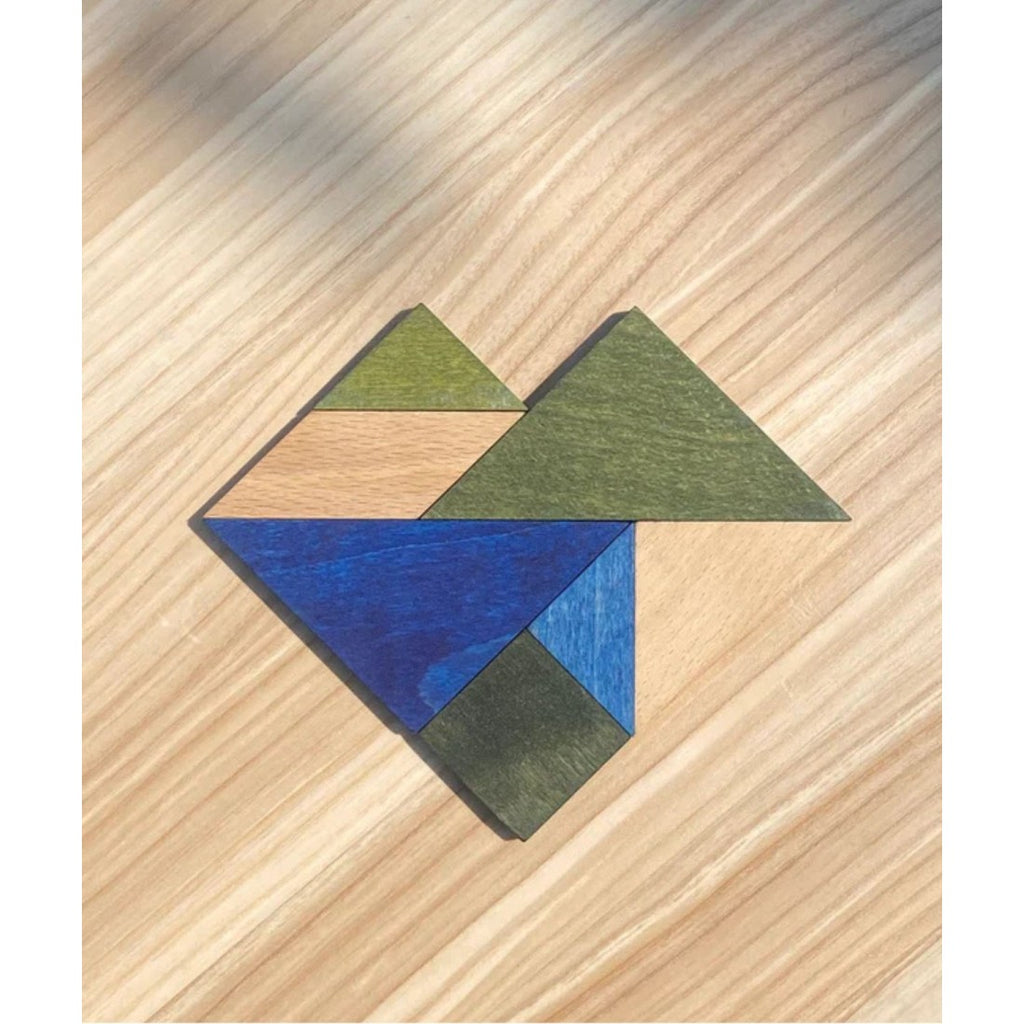 a bold close-up of the cool-toned wooden tangram puzzle pieces laid out on a modern leather bag