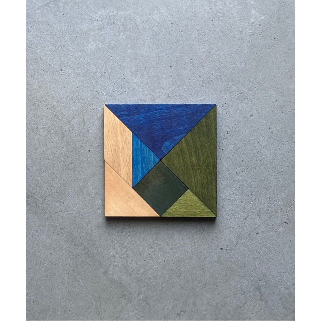 a soft-focus shot of the cool-toned wooden tangram puzzle resting on a cozy fabric pouch